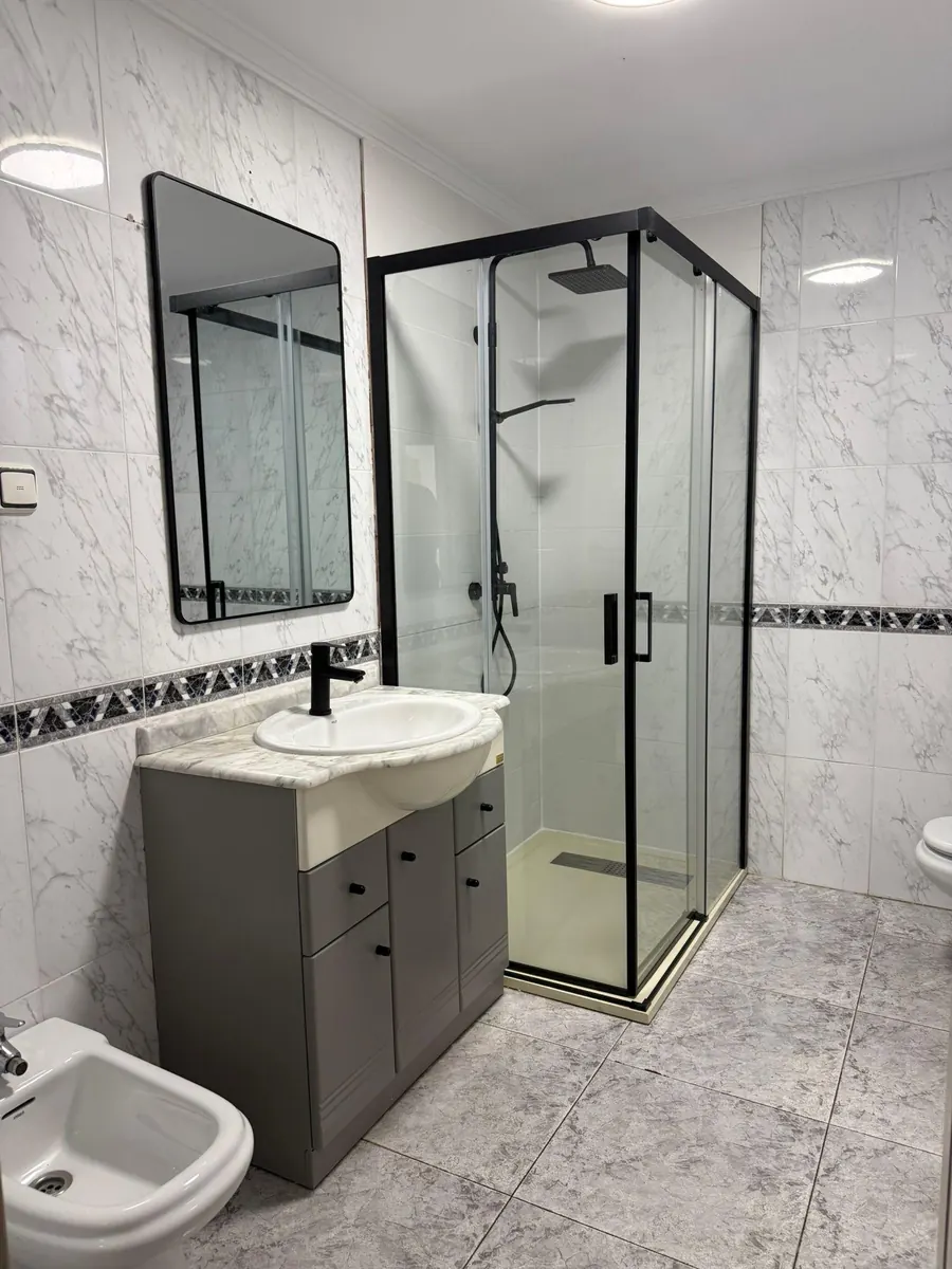 Nieuwe badkamer met douchecabine, meubel en nieuwe tegels